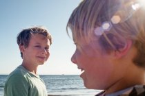 Головний і плечі портрет двох усміхнених хлопчиків, що стоять біля океану . — стокове фото