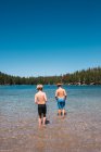 Rückansicht von zwei Jungen in Badehosen, die im Lake Mary, Mammoth Lakes, Kalifornien, USA stehen. — Stockfoto