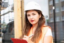 Bauarbeiter macht sich Notizen auf Klemmbrett — Stockfoto
