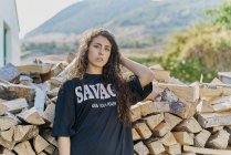 Portrait of young woman with long hair, by log pile — Stock Photo