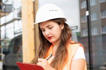 Bauarbeiter macht sich Notizen auf Klemmbrett — Stockfoto