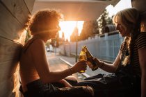 Young female couple toasting with beer bottles in back of van — Stock Photo