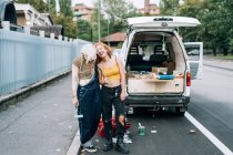 Glückliches weibliches Paar, das neben seinem Lieferwagen steht — Stockfoto