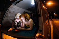 Молода пара лесбіянок дивиться на телефон позаду свого фургона — стокове фото