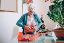 Mujer envolviendo regalos de Navidad - foto de stock