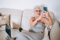 Mulher fazendo videochamada em seu telefone em casa — Fotografia de Stock
