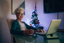 Mulher no laptop chamada de vídeo, árvore de Natal no fundo — Fotografia de Stock