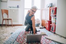 Woman following online yoga class with her cat — Stock Photo
