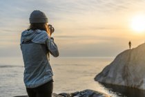 Photographer at coast, photographing friend in distance, Ontario, Canada — Stock Photo