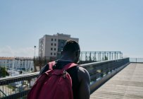 Young man walking across bridge — Stock Photo