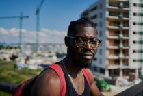Молодий чоловік в окулярах, будівлях на задньому плані — стокове фото