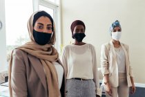 Empresárias usando máscaras faciais no escritório — Fotografia de Stock