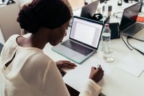 Businesswoman scrivere note e lavorare sul computer portatile — Foto stock