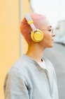 Porträt einer Frau mit kurzen rosafarbenen Haaren, die Kopfhörer trägt — Stockfoto