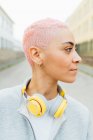 Retrato de mujer joven con el pelo corto de color rosa, con auriculares - foto de stock