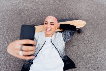 Skateboarder couché à bord et utilisant le téléphone — Photo de stock