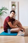 Homem em casa com tapete de exercício e laptop — Fotografia de Stock