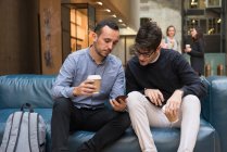 Students on coffee break, looking at phone — Stock Photo