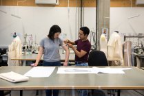 Estudiantes de moda, hombre midiendo el brazo de la mujer - foto de stock