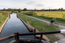 Man cycling beside canal lock — Stock Photo