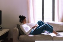 Jeune femme lisant sur canapé — Photo de stock