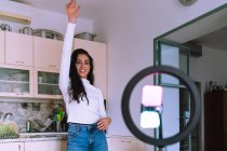 Молодая женщина делает видео дома, используя мобильный телефон и кольцо — стоковое фото