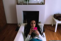 Junge Frau auf dem Sofa und schaut aufs Handy — Stockfoto