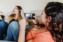 Junge Frau fotografiert Freunde mit Handy — Stockfoto