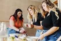 Mujeres amigas preparando comida juntas - foto de stock