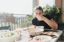 Молода жінка їсть їжу на балконі — стокове фото