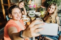 Friends taking selfie at meal on balcony — Stock Photo