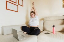 Jovem mulher alongamento, tendo aulas de exercícios online — Fotografia de Stock