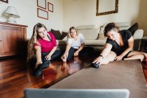 Друзья-женщины растягиваются, вместе ходят на занятия по онлайн-физкультуре — стоковое фото