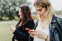 Дві молоді жінки дивляться на свої телефони — стокове фото