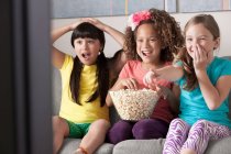Три дівчини дивиться телевізор їсть попкорн — стокове фото