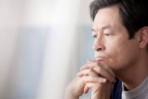 Mature Asian man with hands on chin — Stock Photo