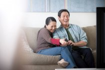 Mature Asian couple watching tv — Stock Photo