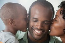Niño y mujer besándose hombre en las mejillas - foto de stock