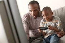 Padre e hijo jugando videojuego - foto de stock