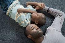 Батько і син лежать спати на підлозі — стокове фото