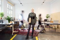 Jeune femme debout dans un espace de co-working créatif occupé — Photo de stock