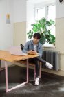 Jovem com telefone e laptop no espaço de co-trabalho — Fotografia de Stock
