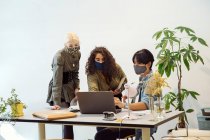 Колеги дивляться на ноутбук, одягнені в маски для обличчя — стокове фото