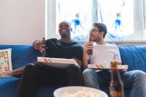 Двое мужчин, пьющих пиццу и пиво дома — стоковое фото