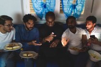 Amici maschi che hanno cibo e guardare il computer portatile — Foto stock