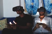 Homens usando fones de ouvido de realidade virtual com telefones inteligentes — Fotografia de Stock