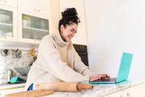 Young woman looking at laptop in kitchen — Stock Photo