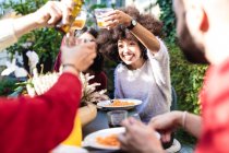 Friends eating meal together outdoors, raising a toast with drin — Stock Photo