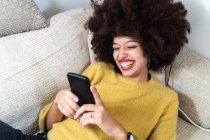 Молодая женщина смотрит на телефон и смеется — стоковое фото