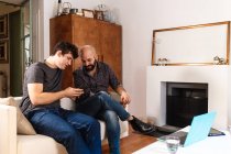 Чоловіки друзі вдома, дивлячись на телефон — стокове фото